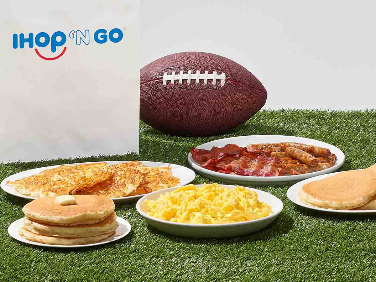 Plates of IHOP food sit are on turf, with a football and IHOP ‘N GO bag behind them.