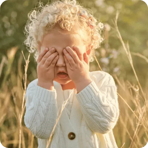 a little girl covering her eyes a little girl covering her eyes
