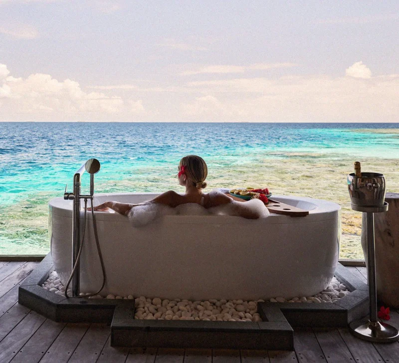 Image Description: A traveler in a hot tub that overlooks the ocean  at a luxury resort in the Maldives