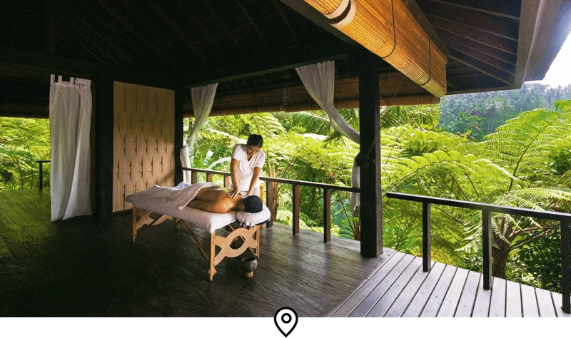 Image Description: A traveler receiving a full-body massage on an open-air terrace with views of the surrounding rainforest in Bali, Indonesia