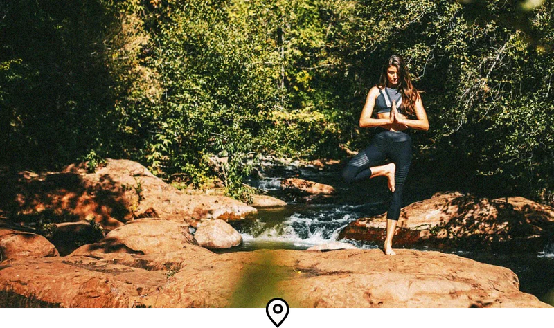 Image Description: A yogi holding a tree pose next to a small stream in Sedona, Arizona