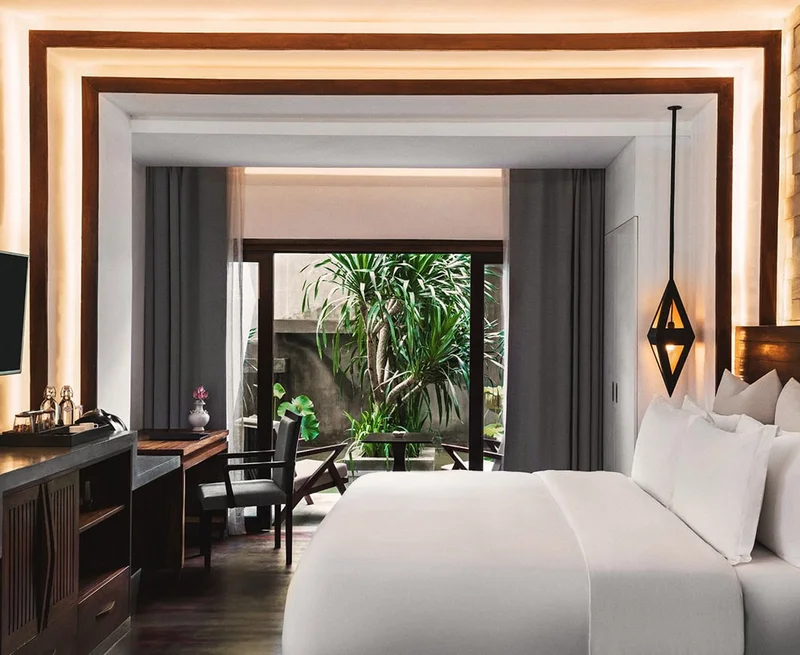 Image description: A modern, airy hotel room with a view of a garden courtyard.