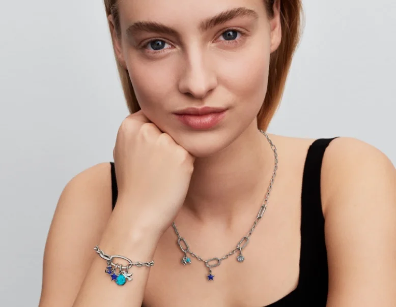 A model wears a sterling silver Pandora ME link chain bracelet and necklace with blue charms.