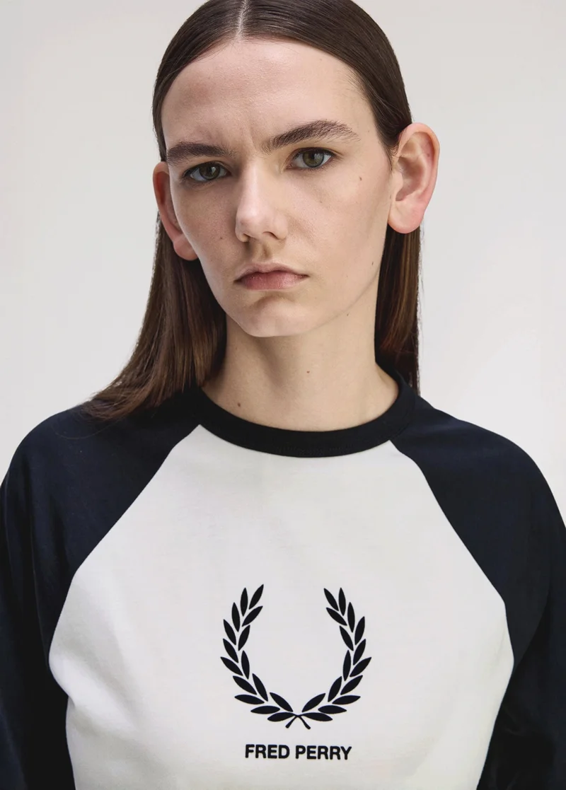 White female model with long brunette straight hair wears a black and white colour block t-shirt with a large printed laurel wreath logo at the front