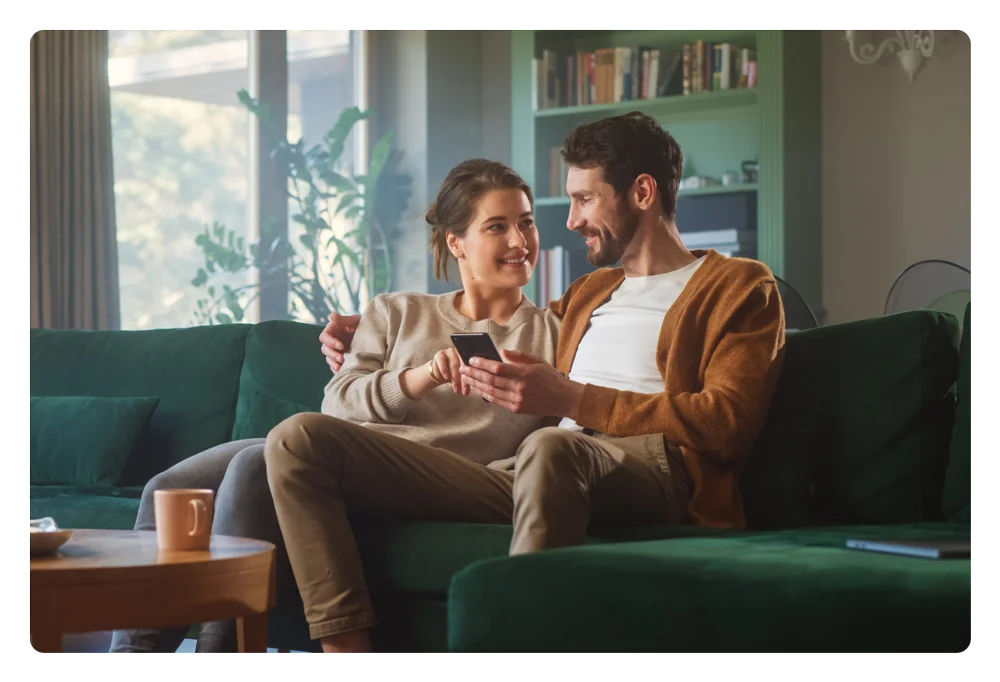 People looking at their phone while sitting on the couch.