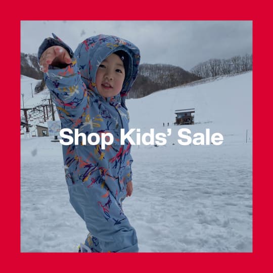 A darkened image of a Kid wearing the toddler one piece in a blue print in the background. The text 'Shop Kid's Sale' is in white on top.