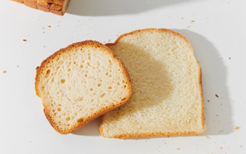 Two slices of white bread and two sliced loaves of bread are pictured.