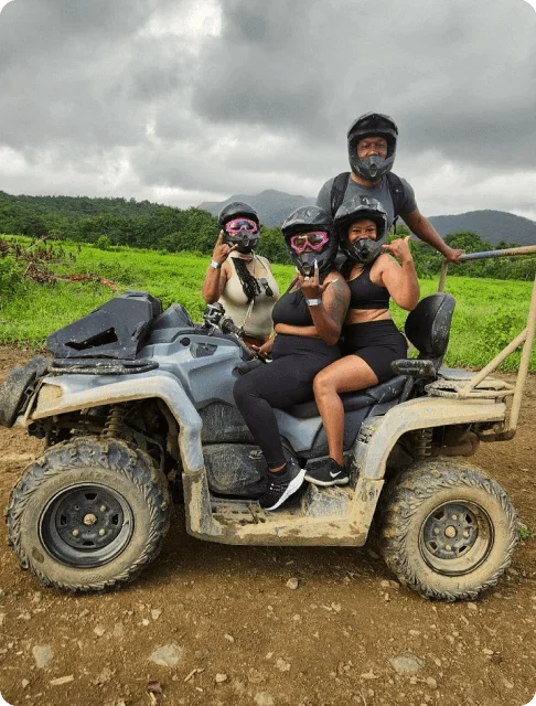 Image Description: A group of travelers wearing helmets posing for the camera on a muddy ATV