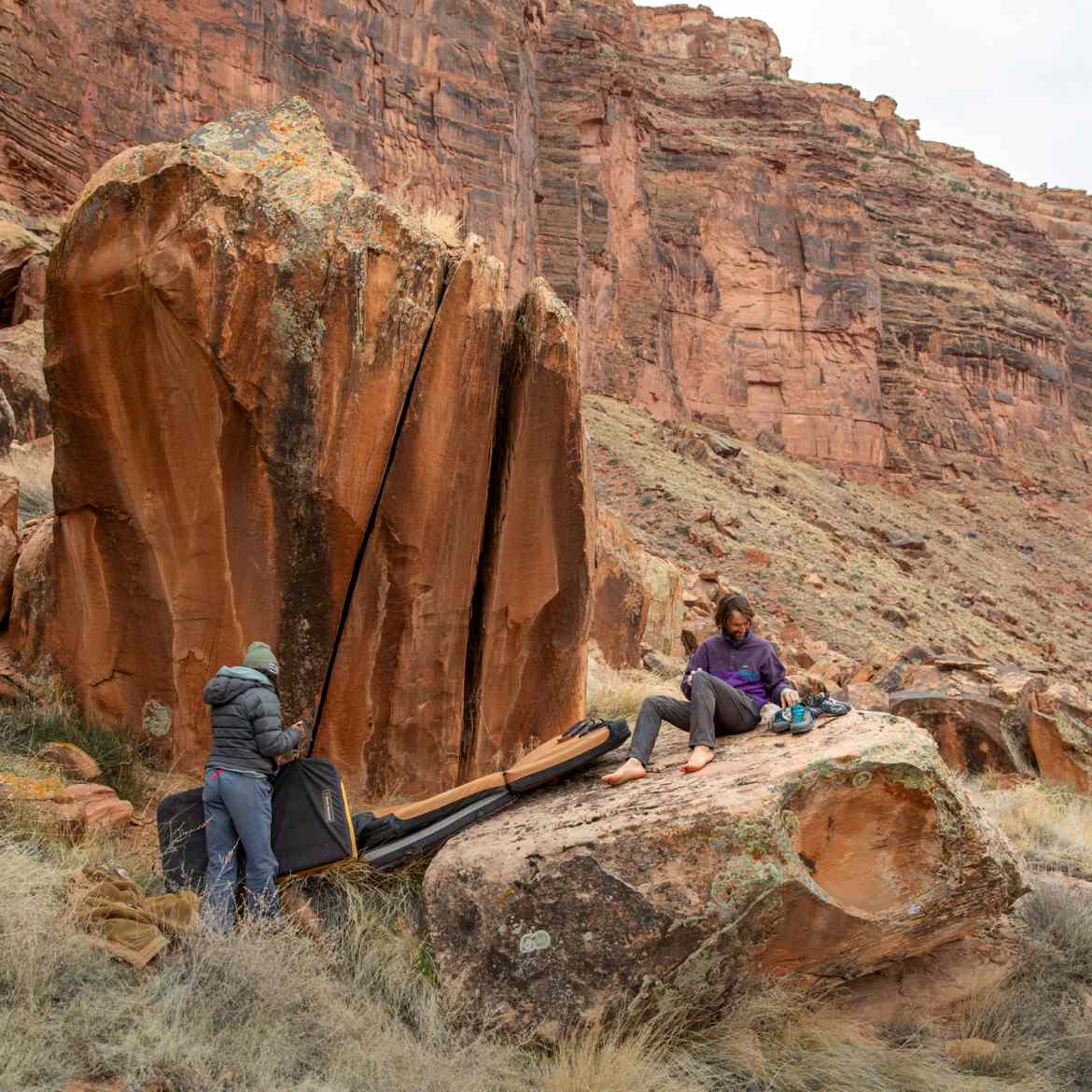 Two people prepare to climb a rock in a canyon.