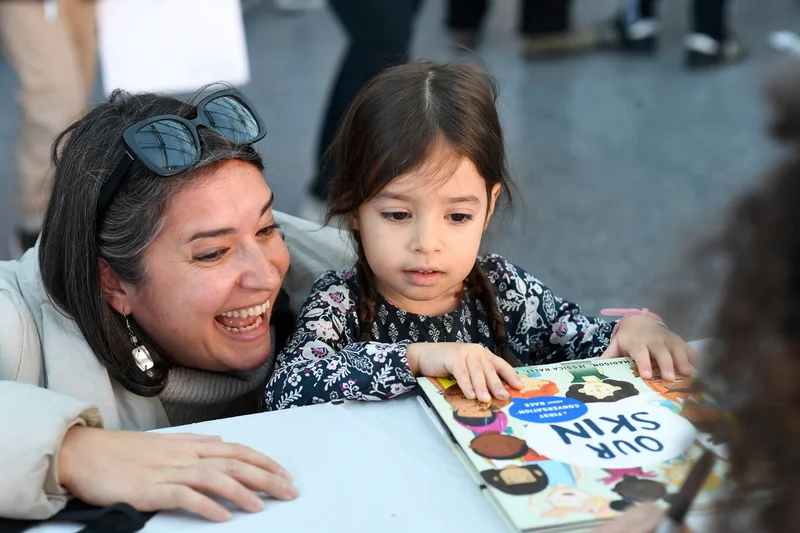 A photograph of a woman and child looking at a book