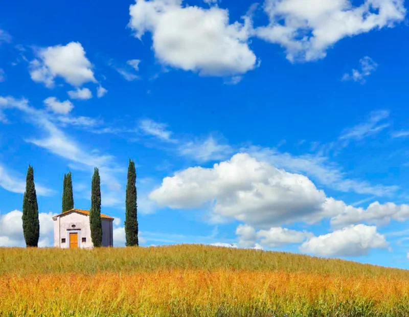 a small country church and cypress trees in Valdera valley, Tuscany, Italy