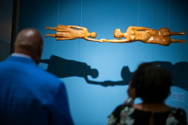 Two people looking at art by Elizabeth Catlett