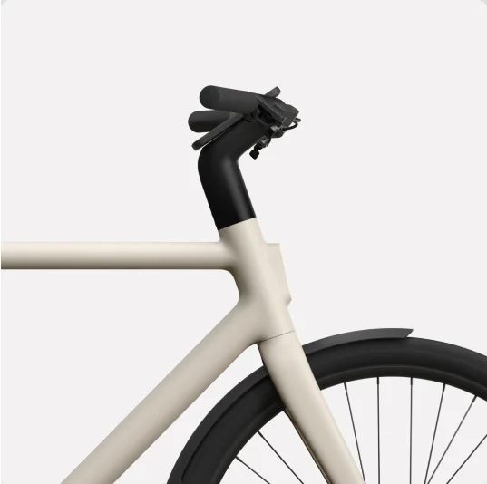 Alt text: “Close-up side view of the front frame, handlebars, and wheel of a Cowboy bike in a light beige colour, showcasing its sleek design.”