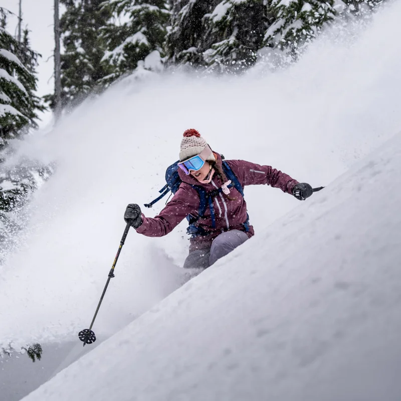 A skiier taking a turn on a snowy mountain.