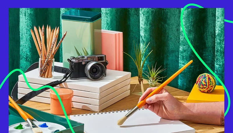 Image showing a hand holding a brush over a notebook and different items on the background