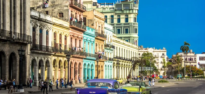 View of downtown Havana city with old classic cars and people walking on the street, Cuba.