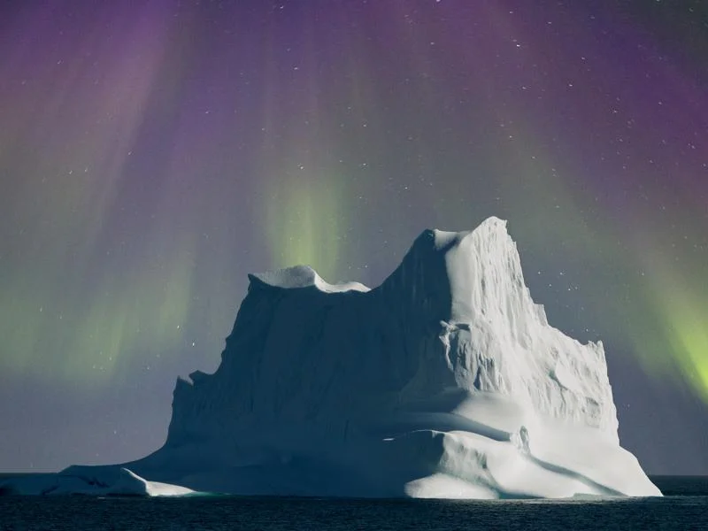 Pink and Green Northern lights formed like a cloak over a massive iceberg in North East Greenland.