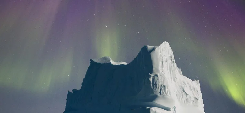 Pink and Green Northern lights formed like a cloak over a massive iceberg in North East Greenland.