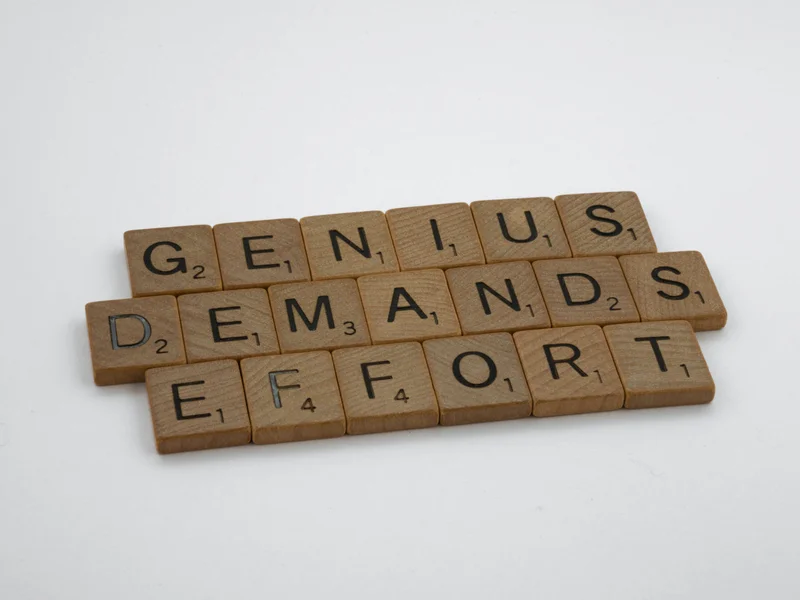 Scrabble tiles that spell out, “Genius demands effort.”