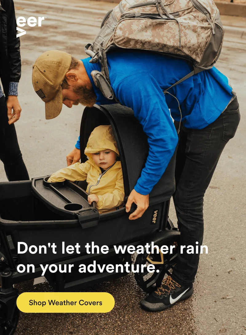 a man sets a veer cruiser canopy for his child to shield from the rain