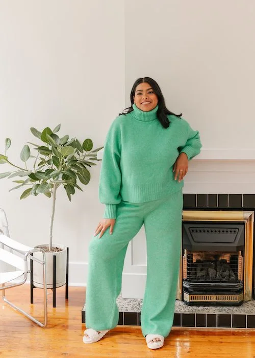 woman wearing turquoise knitted set in front of gas fireplace