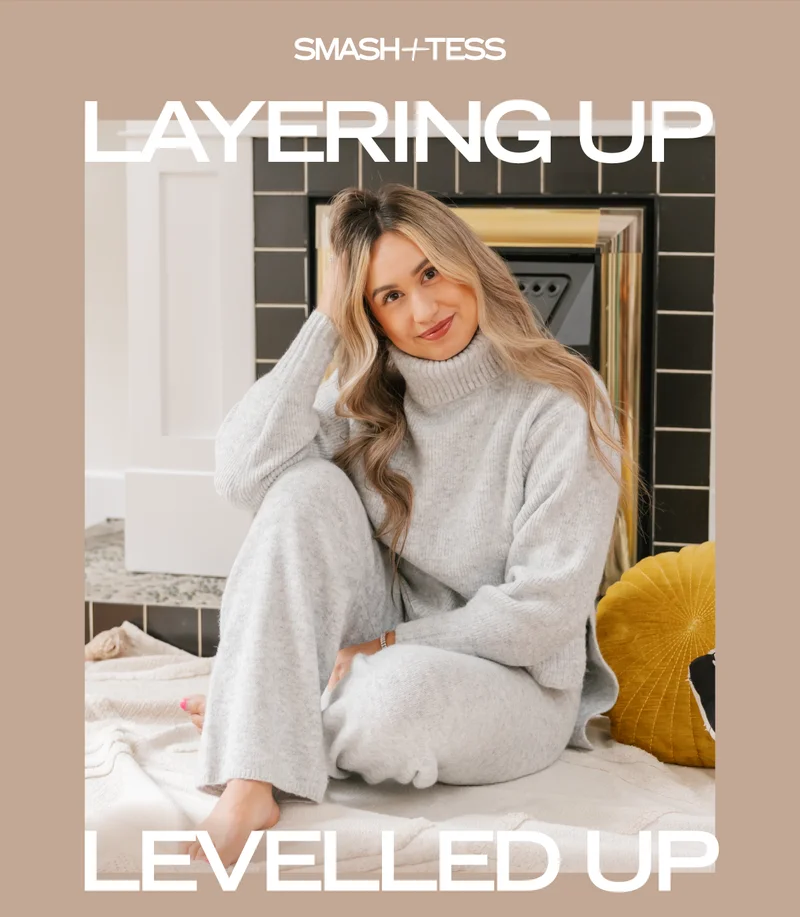 woman wearing grey knitted set sat in front of fireplace with caption 'layering up, levelled up'