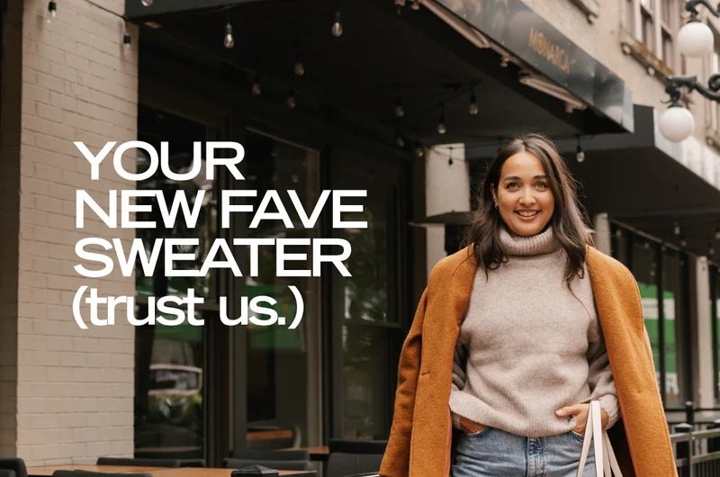 brown haired woman wearing beige sweater and brown wool coat walking past restaurant