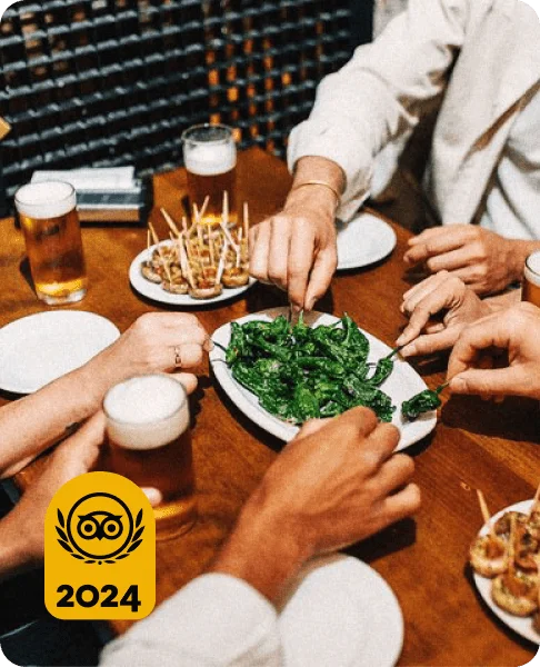 Image Description: Travelers sharing a plate of green peppers at a tapas bar