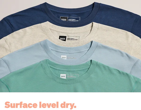 Stack of SAXX cooling cotton t-shirts in multiple colors with “Surface level dry” text overlay.
