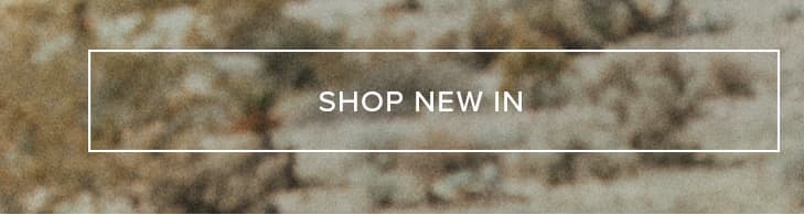 White 'SHOP NEW IN' button with a crisp border, on a soft, variegated background of earthy brown and cream tones. Explore the latest new arrivals.