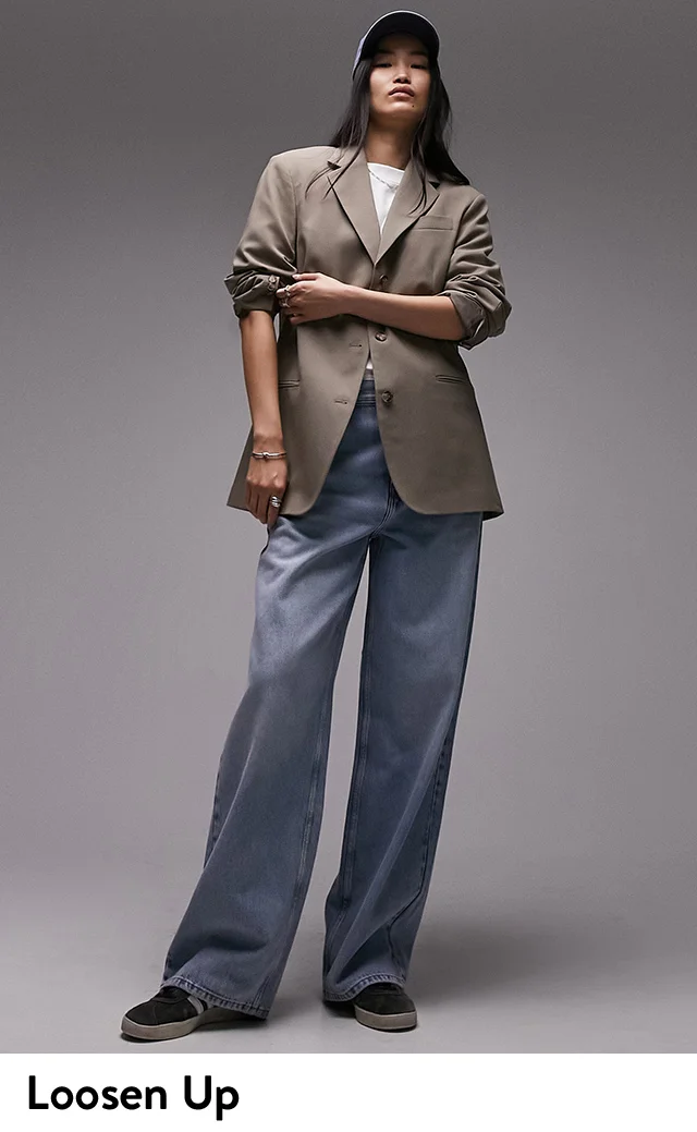 A woman wearing an oversized tan blazer, white shirt and wide-leg jeans.