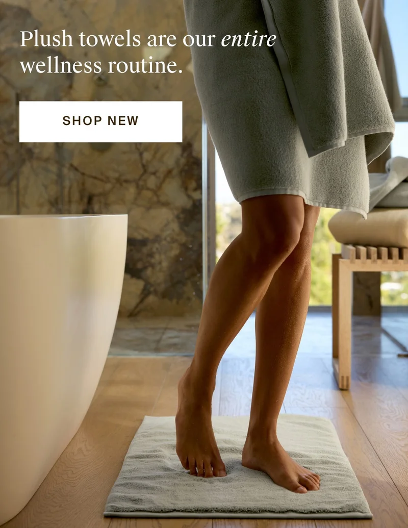 Woman in towel standing on plush tub mat. Shop New