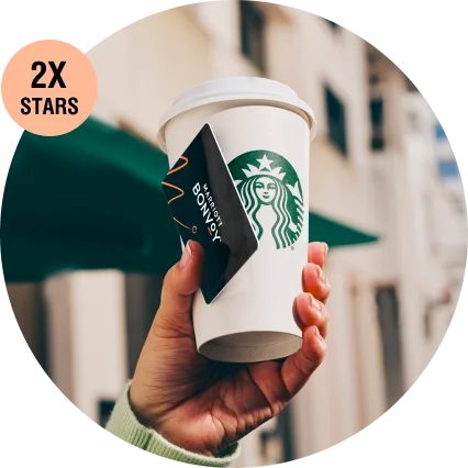 A closeup of someone holding a Marriott Bonvoy key card and Starbucks beverage.