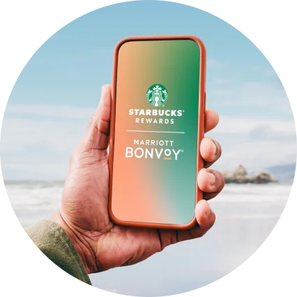 A mobile device with Starbucks Rewards and Marriott Bonvoy logos on the screen.