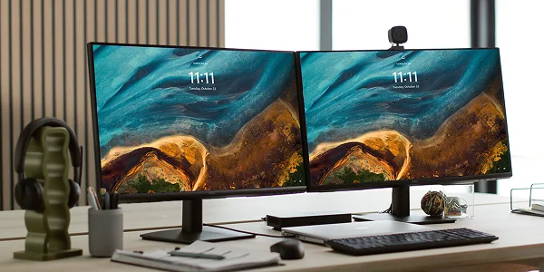 A Dell laptop computer, with two monitors, a dock, webcam, wireless keyboard and mouse on an office desk.