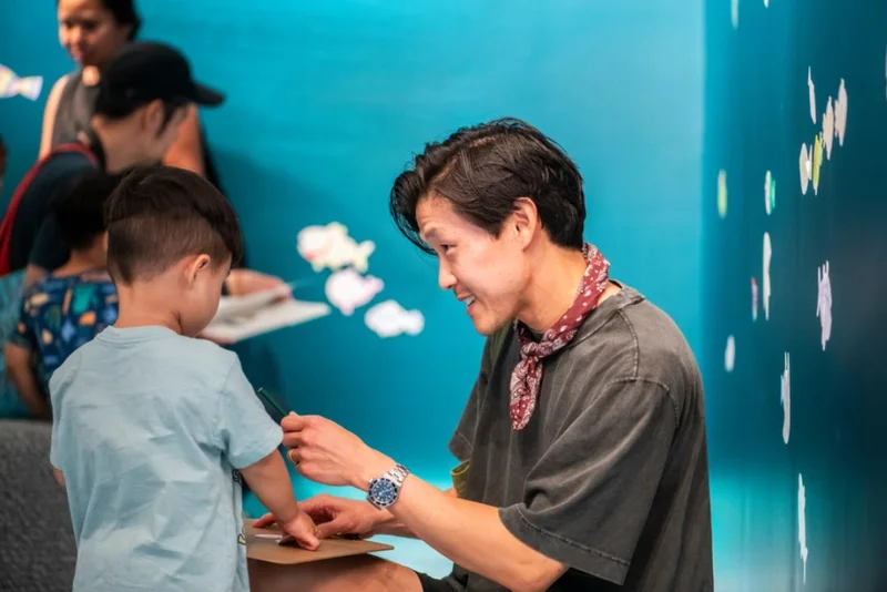 A parent and child make art in a gallery painted blue