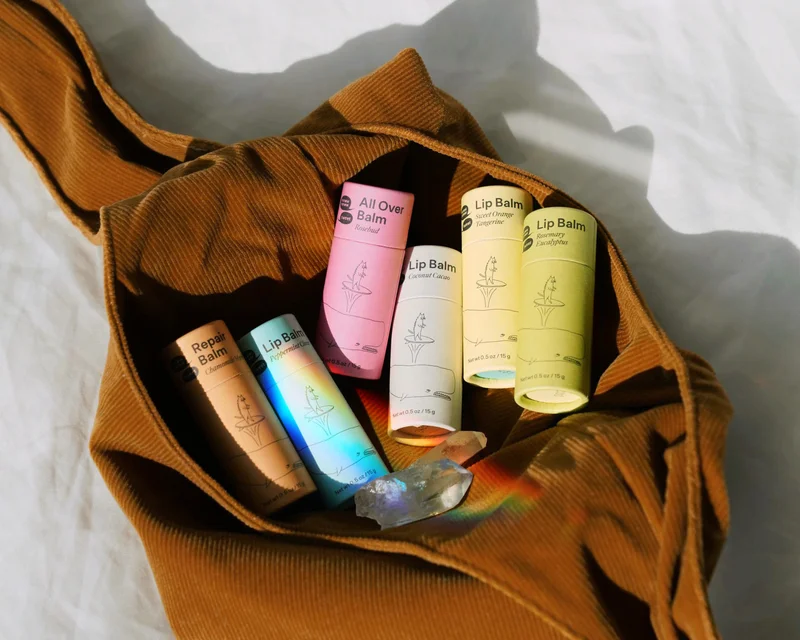 A collection of lip balms is in a jumbled pile in a brown purse