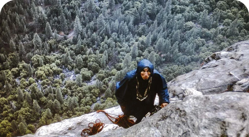An old photo of a person rock climbing.