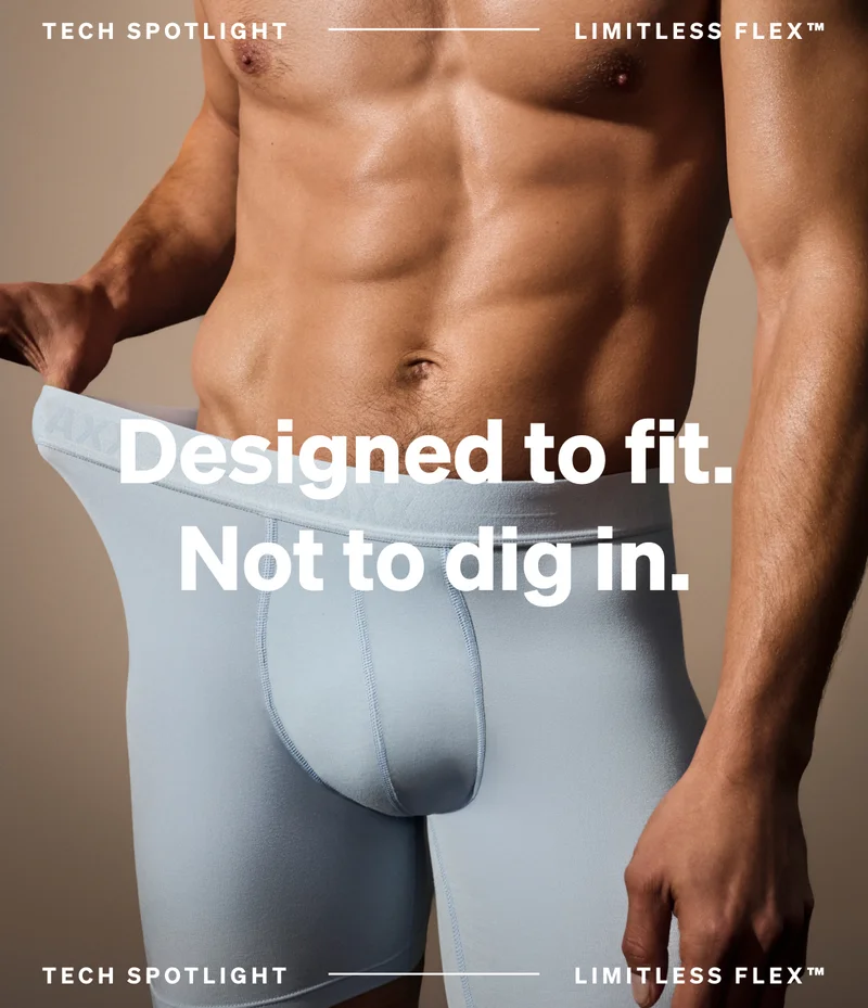 Model wearing light blue SAXX boxer brief with waistband stretch, featuring Limitless Flex technology and “Designed to fit. Not to dig in.” text.