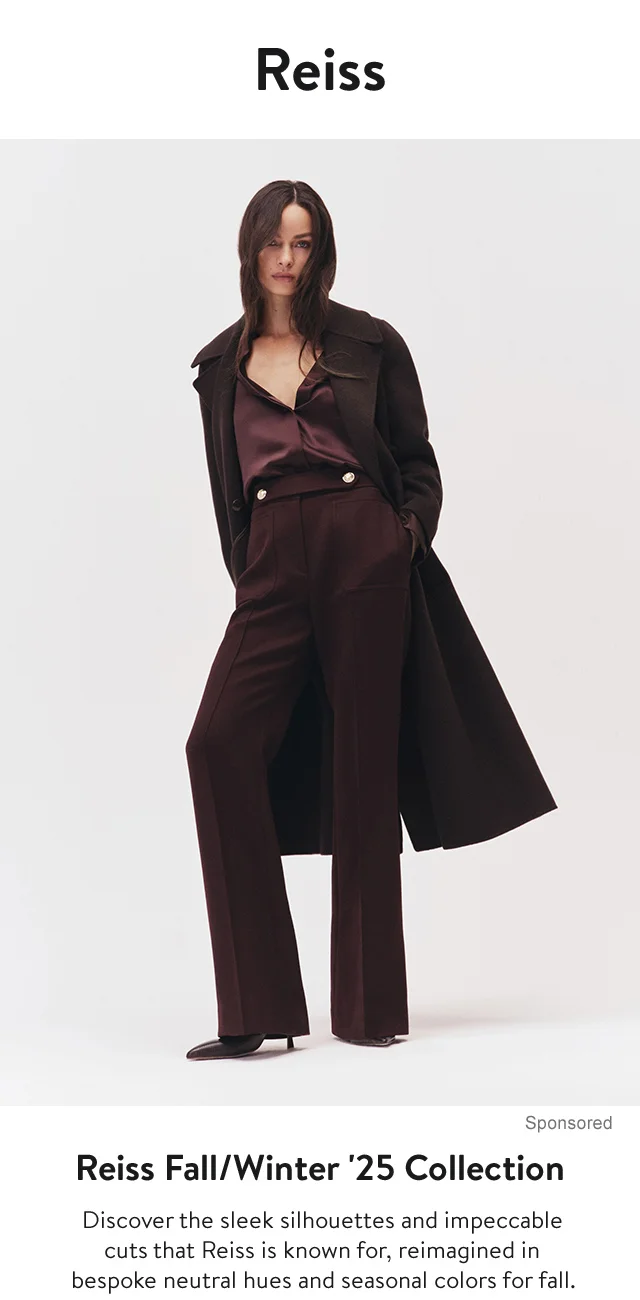 A woman wearing a blouse, trousers and coat, all in burgundy.
