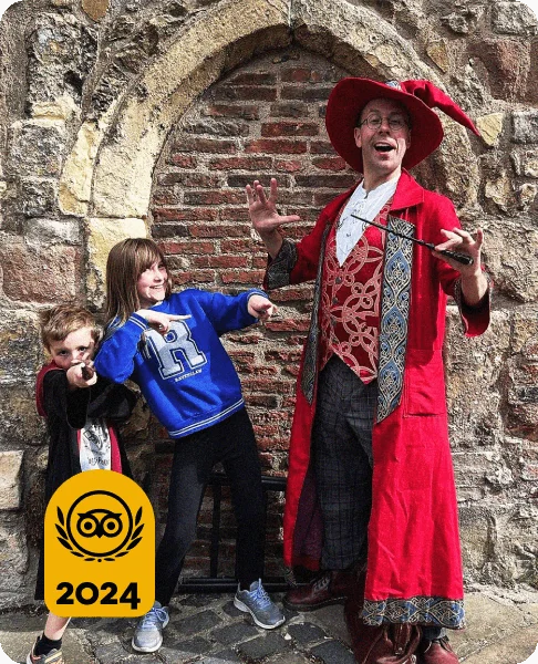 Image Description: Two children posing with wands beside a tour guide dressed in a wizard robe and hat