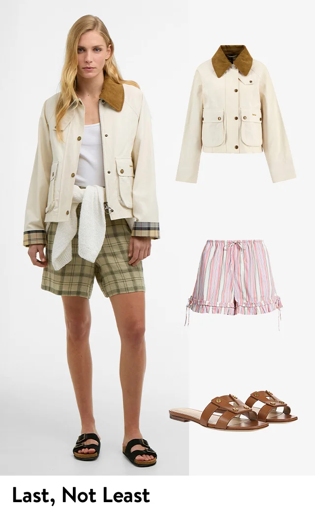 A woman wearing a utility jacket over a tank with a sweater tied around her waist, plaid shorts and sandals.