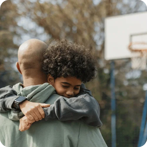 a dad and son hugging at the basketball court a dad and son hugging at the basketball court