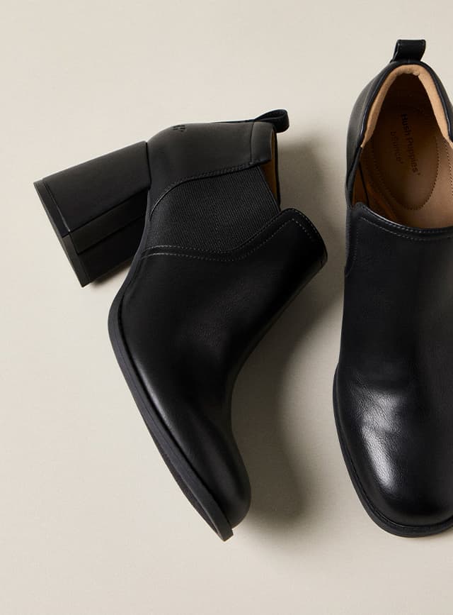 A side and overhead view of the Tayta Bootie designed in black leather with a round toe, elastic panels at the sides, a back pull tab, and chunky block heel.