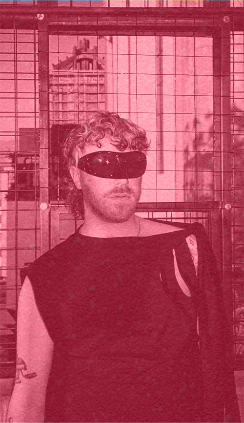 Shane Thomas, wearing futuristic shades, stands in front of a cityscape.