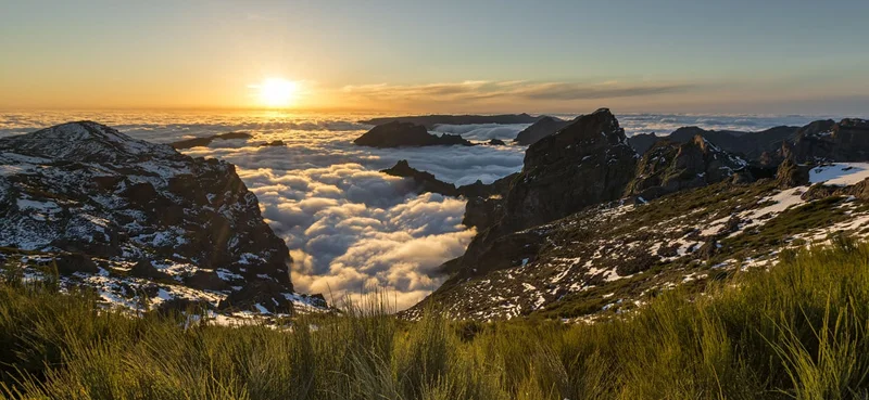 Backlit rocky peaks above clouds at Pico do Arieiro in Madeira, Portugal at sunset.