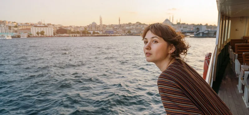 Woman looking at scenic city view while riding ferry through Bosphorus strait in Istanbul.