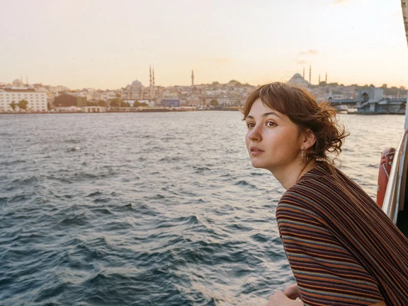 Woman looking at scenic city view while riding ferry through Bosphorus strait in Istanbul.