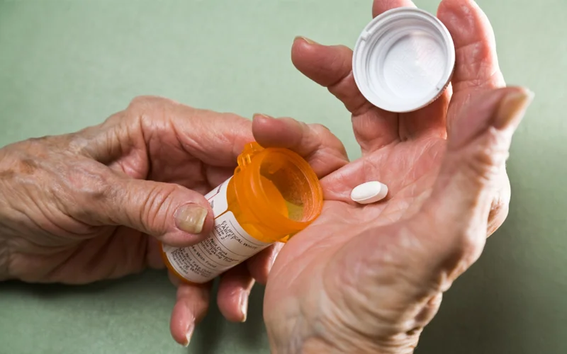 Hands getting pills out of a bottle Hands getting pills out of a bottle
