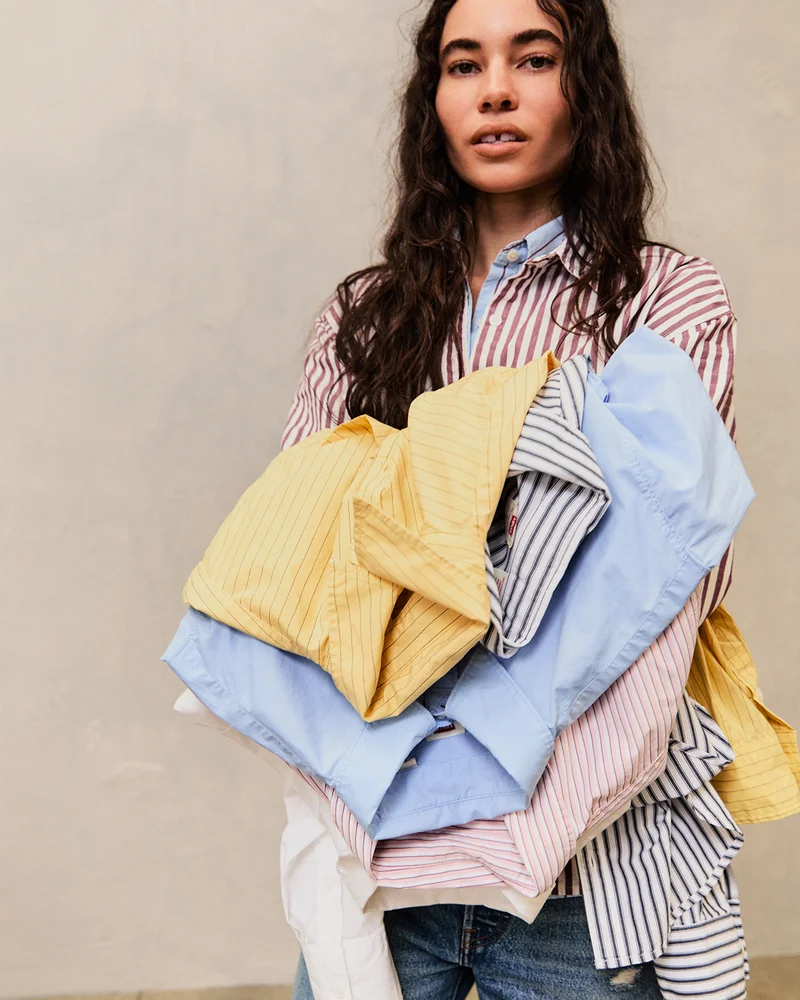 Person holding a stack of striped button up shirts